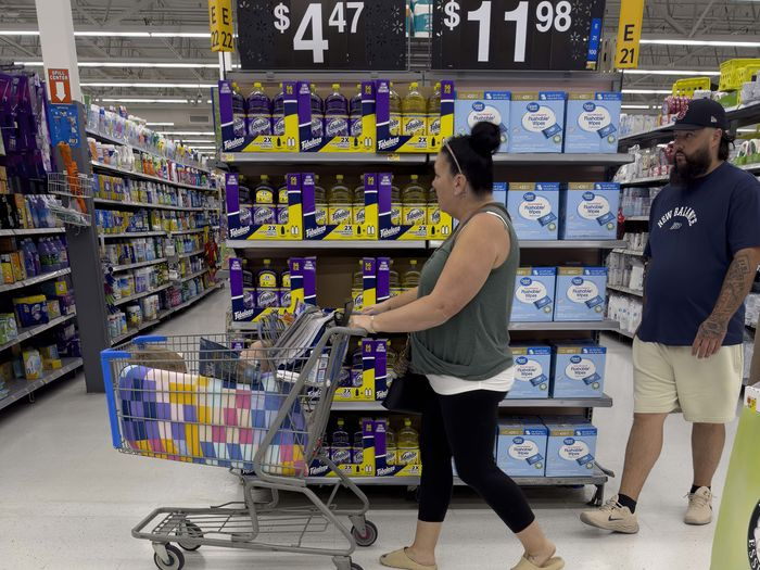 a woman pushes a shopping cart in front of the end of aisle in a large store