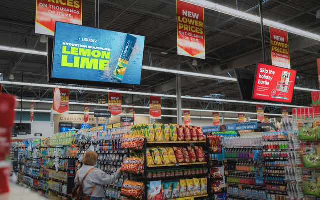 a photo inside of a grocery store. A digital screen can be seen over an aisle