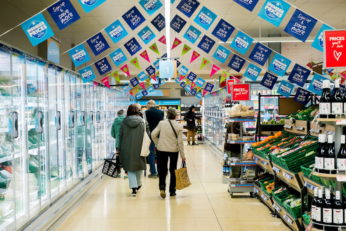 A Photo of shoppers in the aisle of a large supermarket