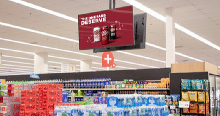 a photo of the inside of a grocery store with a digital screen suspended above the aisle. On the screen an advert for Dr. Pepper can be seen.