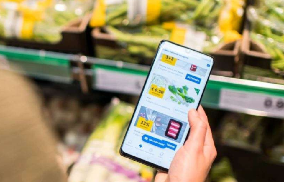 A photo of a hand holding a mobile phone on which the lidl app can be seen.