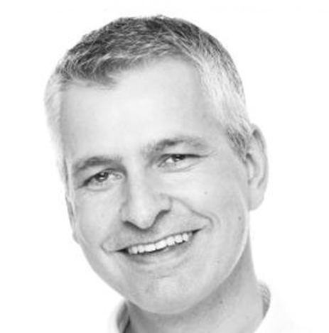 A black and white photo of Simon Miles smiling at the camera