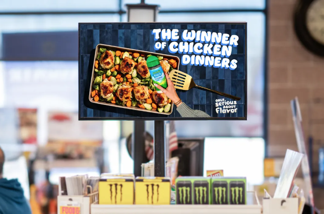 A photo of a landscape orientated screen at a cash register in a grocery store showing an advert for a chicken spice.