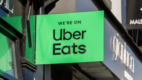 A green sign outside of a building saying "We're on UberEats"
