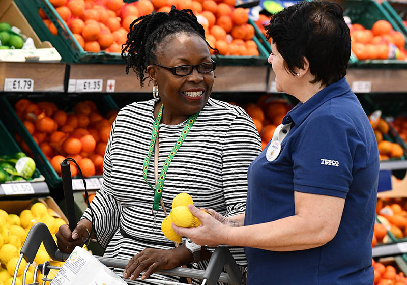 Two people standing in a Tesco supermarket and talking.
